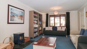 A living room with a sofa, a wooden coffee table, a bookshelf, and a fireplace. - Morgan House (Bridgwater)