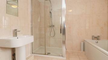 A modern bathroom with a glass-enclosed shower, a white sink, and a bathtub.