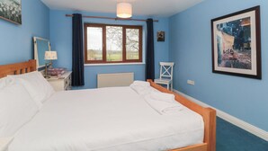 A bedroom with a large bed, a window with curtains, a bedside table with a lamp, and a framed painting on the wall. - Morgan House (Bridgwater)