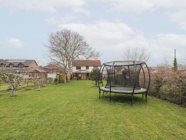 A trampoline in a backyard with a house in the background.