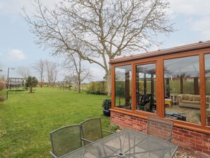 A patio area with a glass enclosure, a table, and chairs. - Morgan House (Bridgwater)