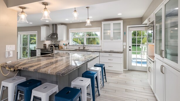 A modern kitchen with a large island, white cabinetry, and a view of the outdoors. - Waterfront - 5 BR, 4 BA, Pool w Tub, 80' Dock, Tiki Hut, Beach Nearby, Parking (Marathon)