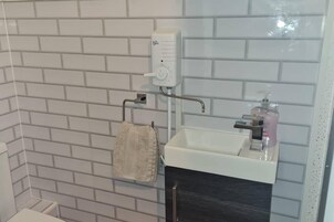 A bathroom with a white sink, a soap dispenser, and a towel hanging on a rack.