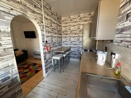 A compact kitchen with a stone-patterned backsplash, a dining area with a small table and chairs, and a built-in stove.