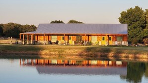 Un edificio rústico con techo metálico, paredes de madera y un reflejo en el agua.