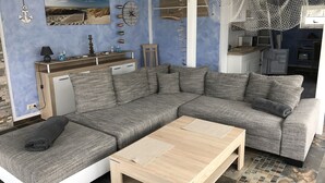 A modern living room with a sectional sofa, a wooden coffee table, and a kitchen in the background.