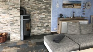 A modern living room with a stone wall, a fireplace, a sofa, and a desk with a lamp.