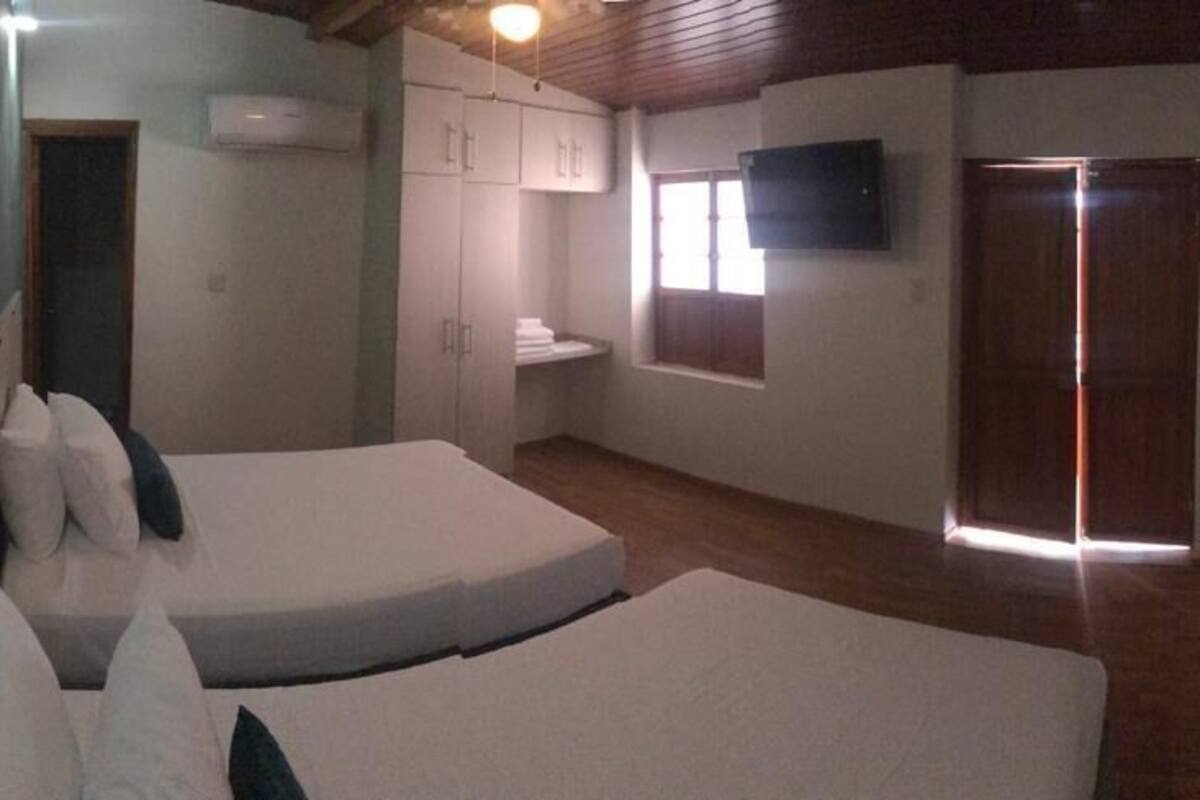A bedroom with two beds, a TV mounted on the wall, and a wooden door.