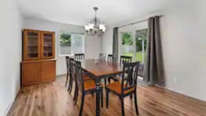 A dining area with a wooden table and chairs, a chandelier, and a cabinet. - Spacious , RV parking, yard, cozy fireplaces, game library, near Manchester (Port Orchard)