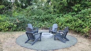 A circular outdoor seating area with Adirondack chairs and a fire pit. - Spacious , RV parking, yard, cozy fireplaces, game library, near Manchester (Port Orchard)