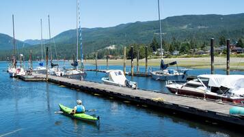 A marina with boats docked at wooden piers, surrounded by a forested landscape.