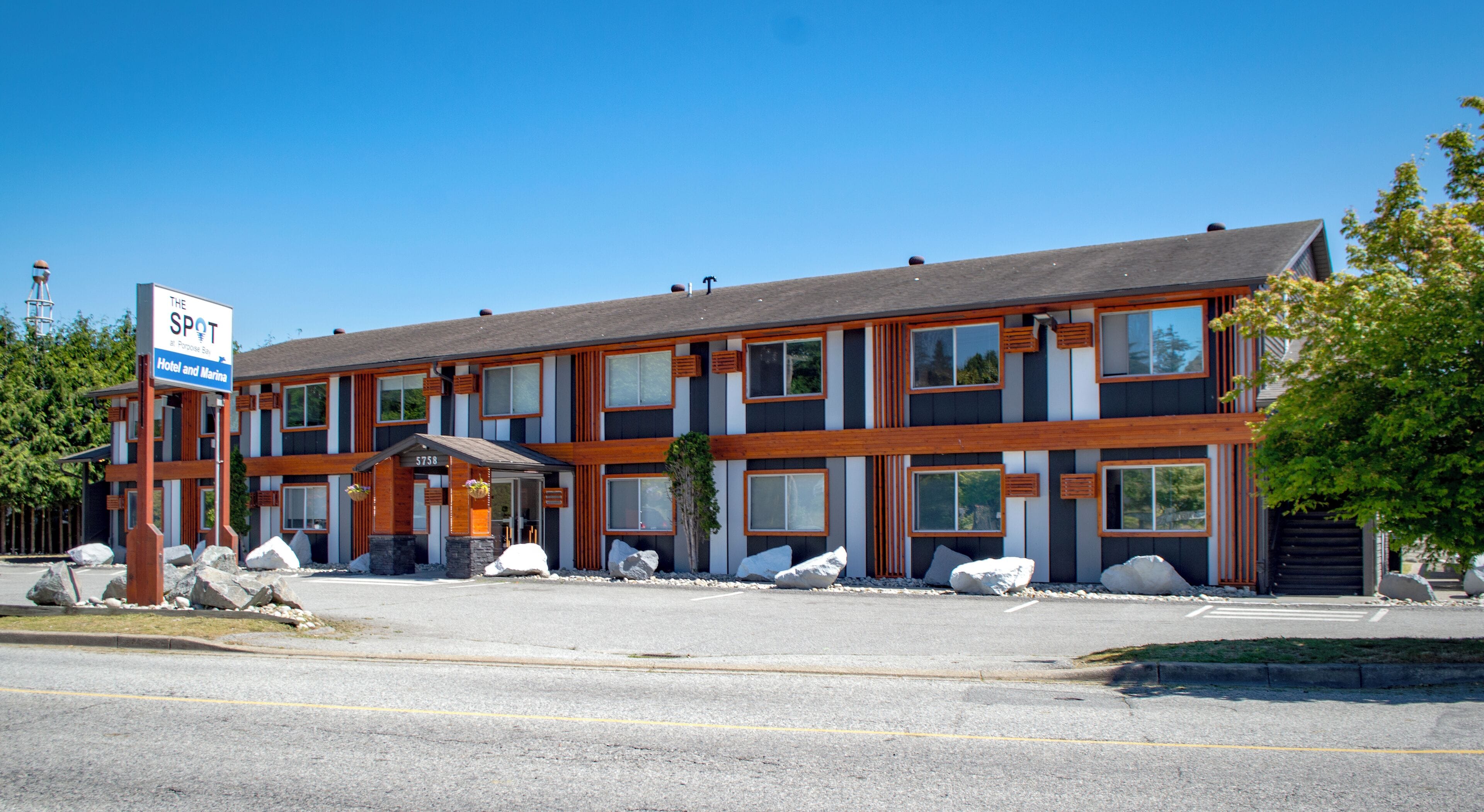 A modern hotel with a sign reading "The Spot Hotel and Marina." It features a multi-story structure with large windows and a covered entrance.