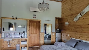 Une chambre avec un mur en bois, un grand lit, un miroir, un lavabo et un lustre.