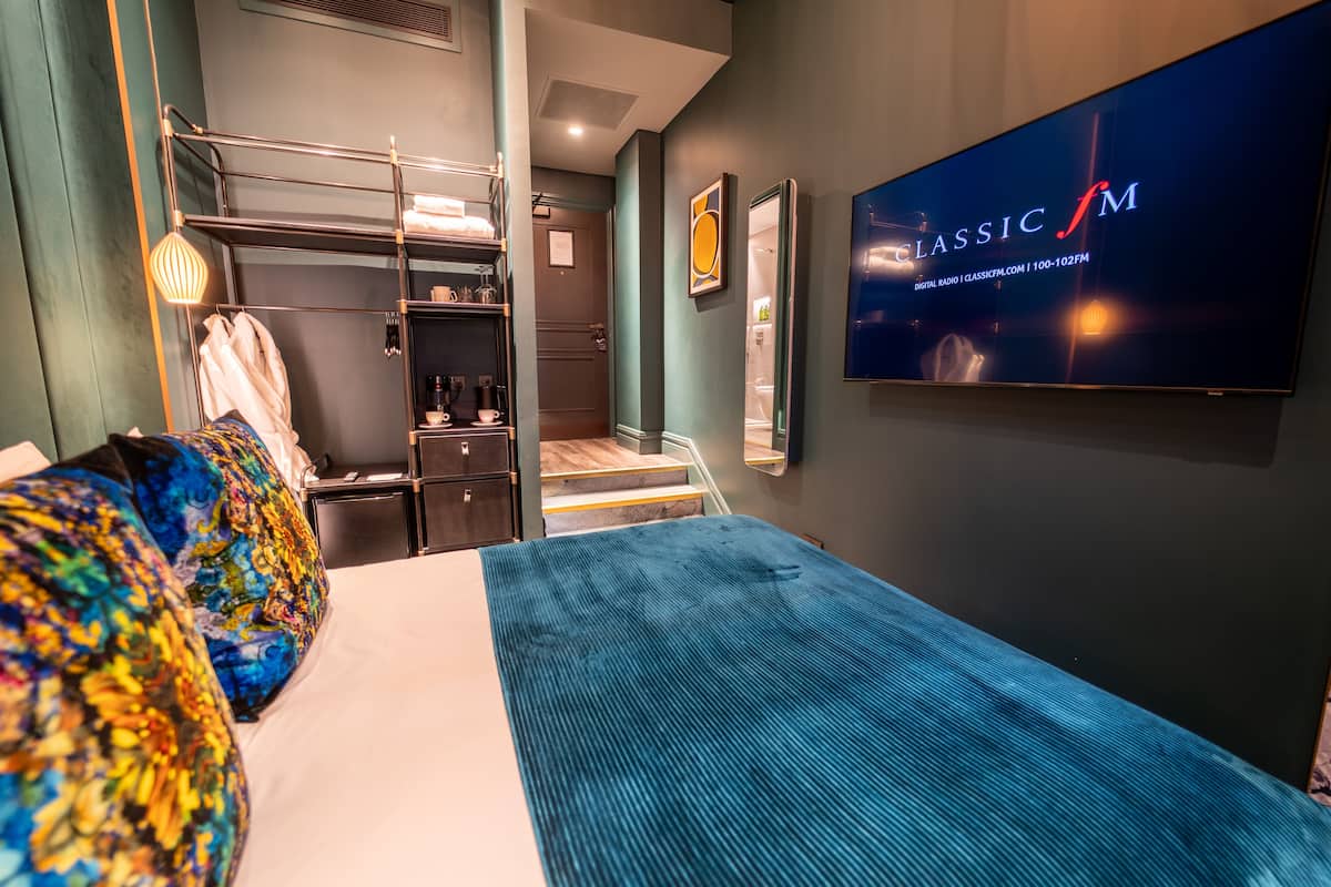 A hotel room with a bunk bed, a flat-screen TV, a desk with a chair, and a wardrobe.