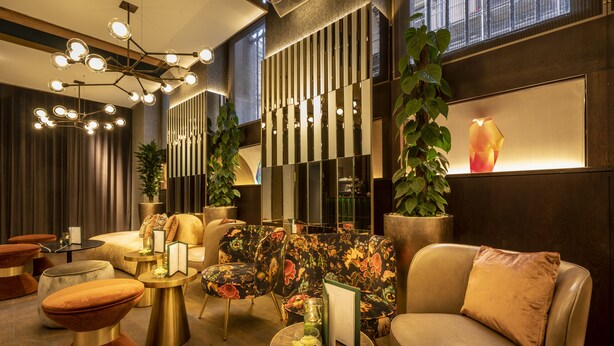 Un espace détente moderne avec un aménagement central des sièges, un luminaire décoratif et une grande plante en pot.