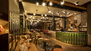 Un espace bar moderne doté d’un comptoir incurvé, de tables rondes et de luminaires suspendus.