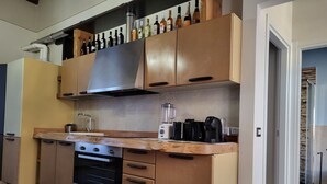 Una cocina moderna con armarios de madera, horno empotrado, cafetera y estante para vinos.