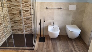 Un baño moderno con cabina de ducha de vidrio, un bidé y un inodoro.