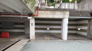 Un estacionamiento vacío con pilares de concreto, piso de baldosas y una barrera de seguridad roja.