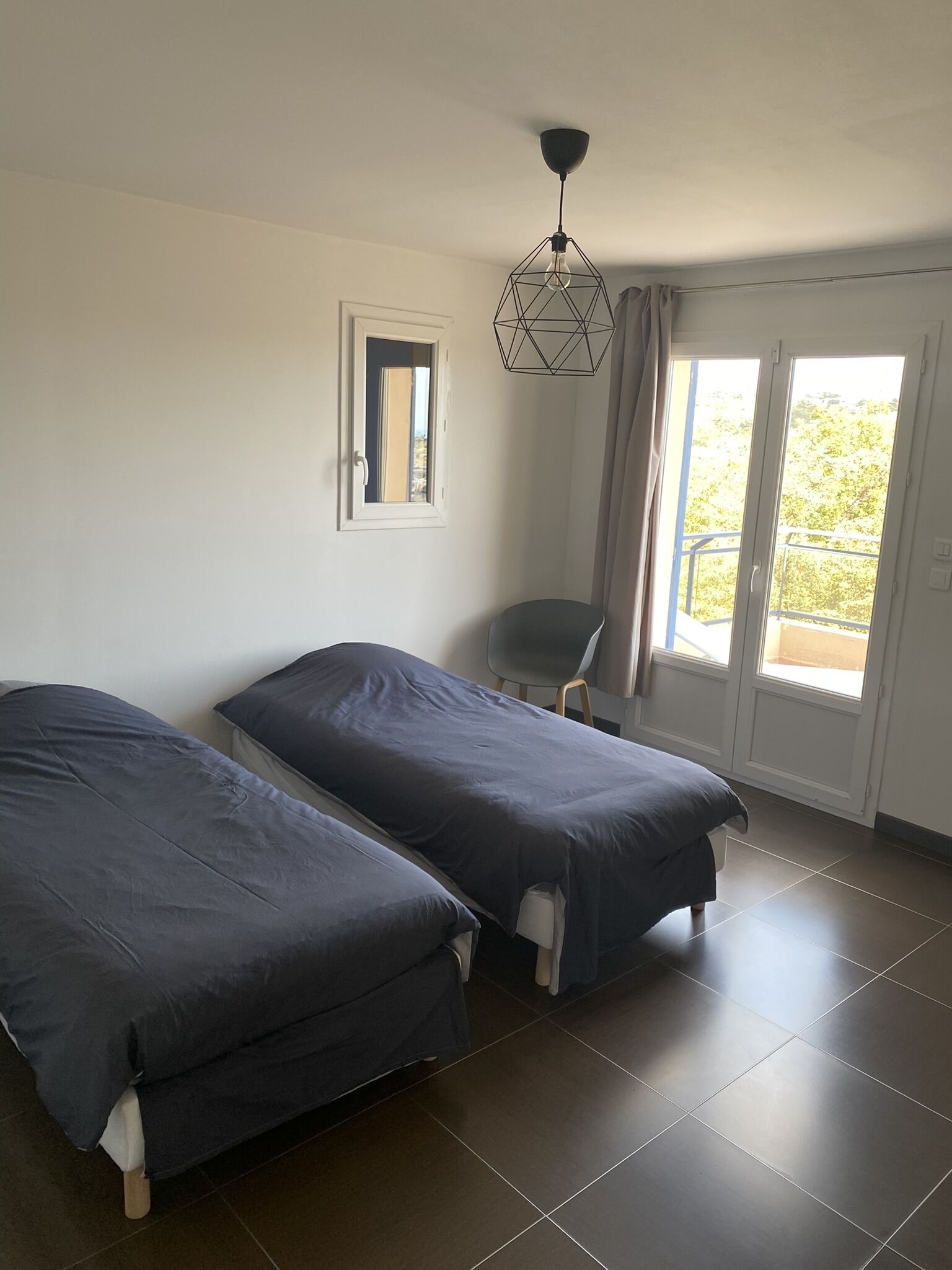 Une chambre avec deux lits, une chaise, une fenêtre et une porte.