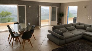 A spacious living area with a glass dining table, grey sofa, and a balcony with a view. - Spacious villa with pool in Nice (Nice)