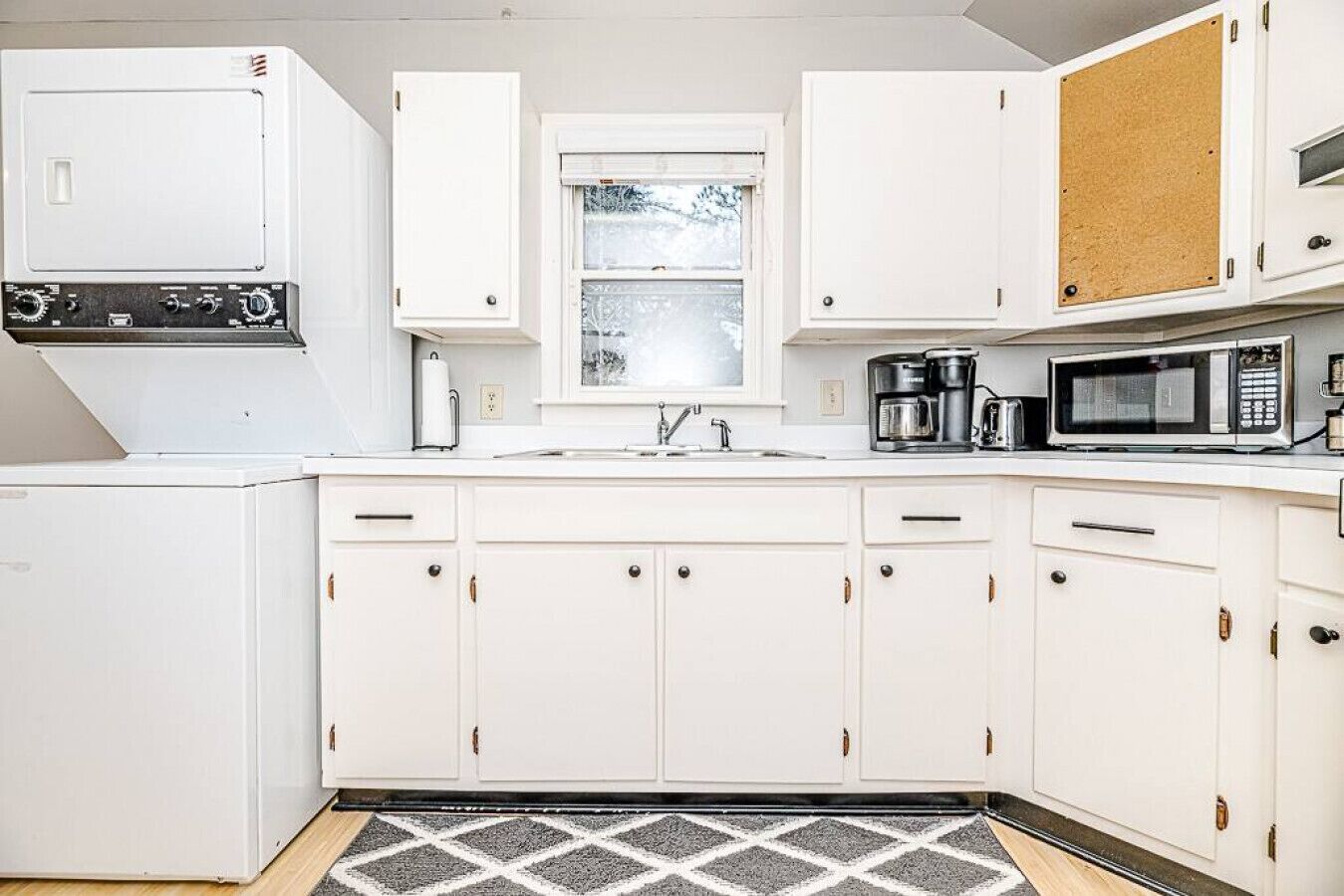 A kitchen with white cabinets, a microwave, a coffee maker, and a refrigerator.