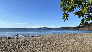 A beach with people and dogs, clear blue sky, and calm sea. - Pacifico Luxury 3B/2B condo, 10 minutes walk to the beach (Playa Del Coco)