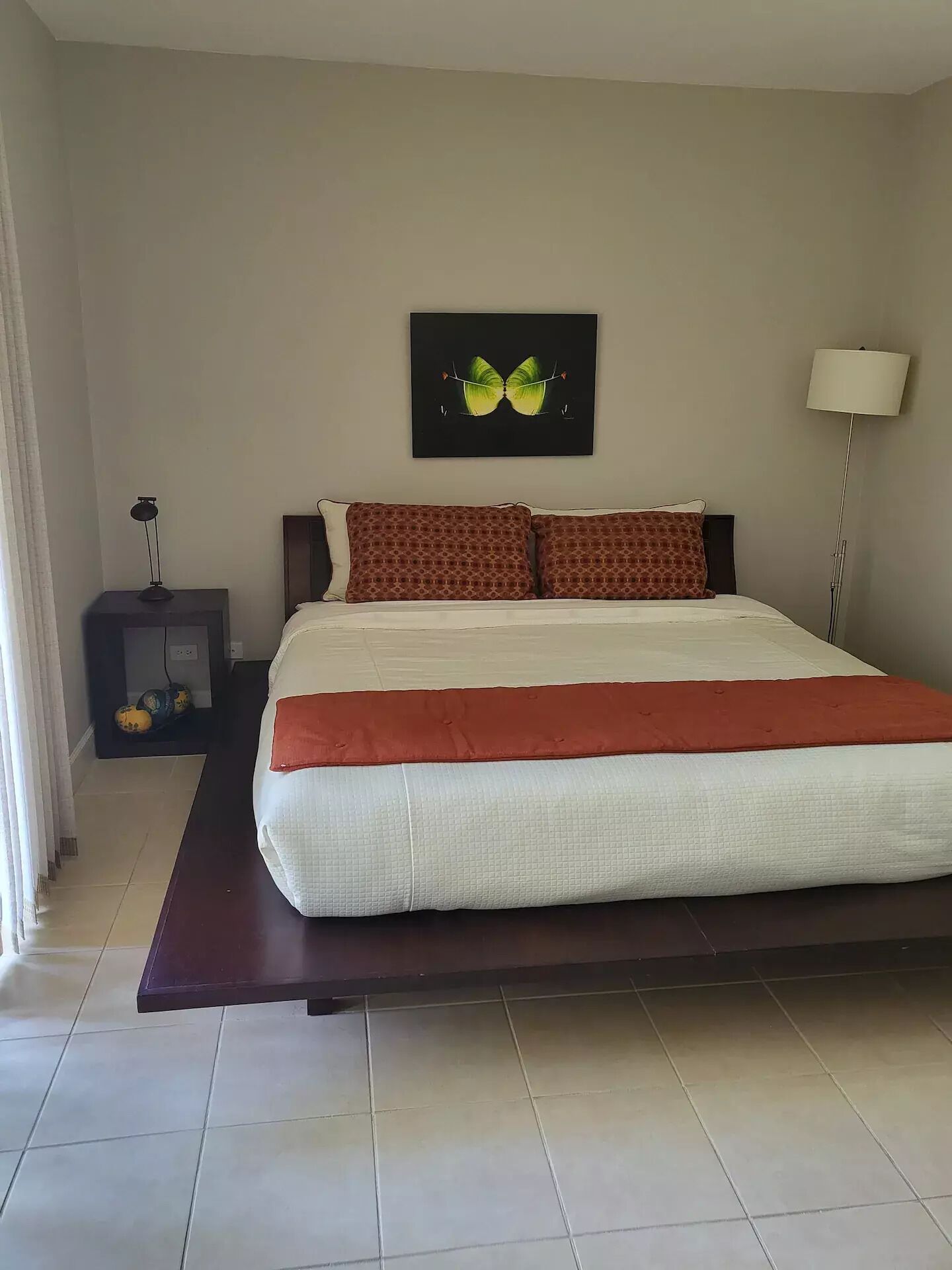 Une chambre d’hôtel bien aménagée, avec un grand lit, une table de chevet avec une lampe, une œuvre d’art accrochée au mur et un lampadaire.