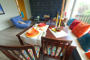 A dining area with a wooden table set for four, surrounded by colorful chairs.