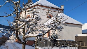A snow-covered building with a stone wall and a metal fence in front. - Vacation apartment Maar-Idyll, quiet, modern vacation apartment with freedom of movement (Schalkenmehren)