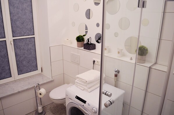 Une salle de bain moderne équipée de toilettes, d’un lave-linge et d’une fenêtre donnant sur un beau paysage.