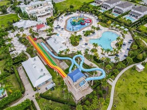 An aerial view of a resort with a water park, including slides and pools, surrounded by lush greenery and guest accommodations. - Themed beds, private pool, theater, TWO game rooms (Kissimmee)