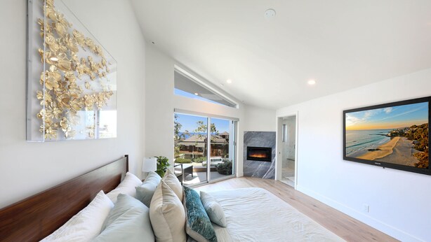 Un dormitorio moderno con una cama grande, una chimenea y una vista panorámica a través de la puerta de cristal.