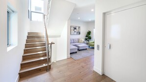 Un interior moderno con una escalera de madera, un conjunto de sofá gris y una decoración minimalista.