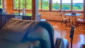 Interior de uma cabana com cozinha, sala de jantar e vista para o exterior.