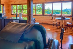 L’intérieur d’une cabane comprend une cuisine, un coin repas et une grande fenêtre donnant sur la forêt.