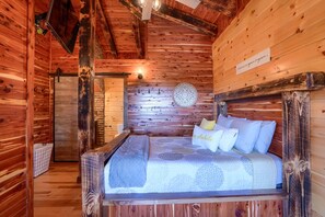 Une chambre dans un chalet en bois, avec un lit, des oreillers, une horloge murale et un panneau.