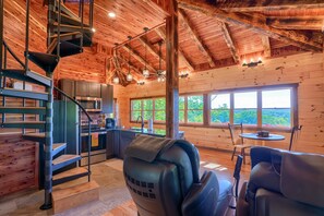 L’intérieur d’une cabane comprend un escalier en colimaçon, un coin cuisine, un espace repas et de grandes fenêtres offrant une vue sur l’extérieur.