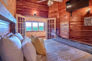A cozy cabin interior with a bed, pillows, a window with a view, and a sign on the wall. - Soaring Eagle Luxury Treehouse (Logan)