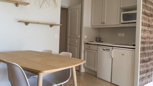 Eine moderne Küche mit weißen Schränken, einer Mikrowelle und einem Geschirrspüler. Ein Holztisch mit Stühlen steht daneben.