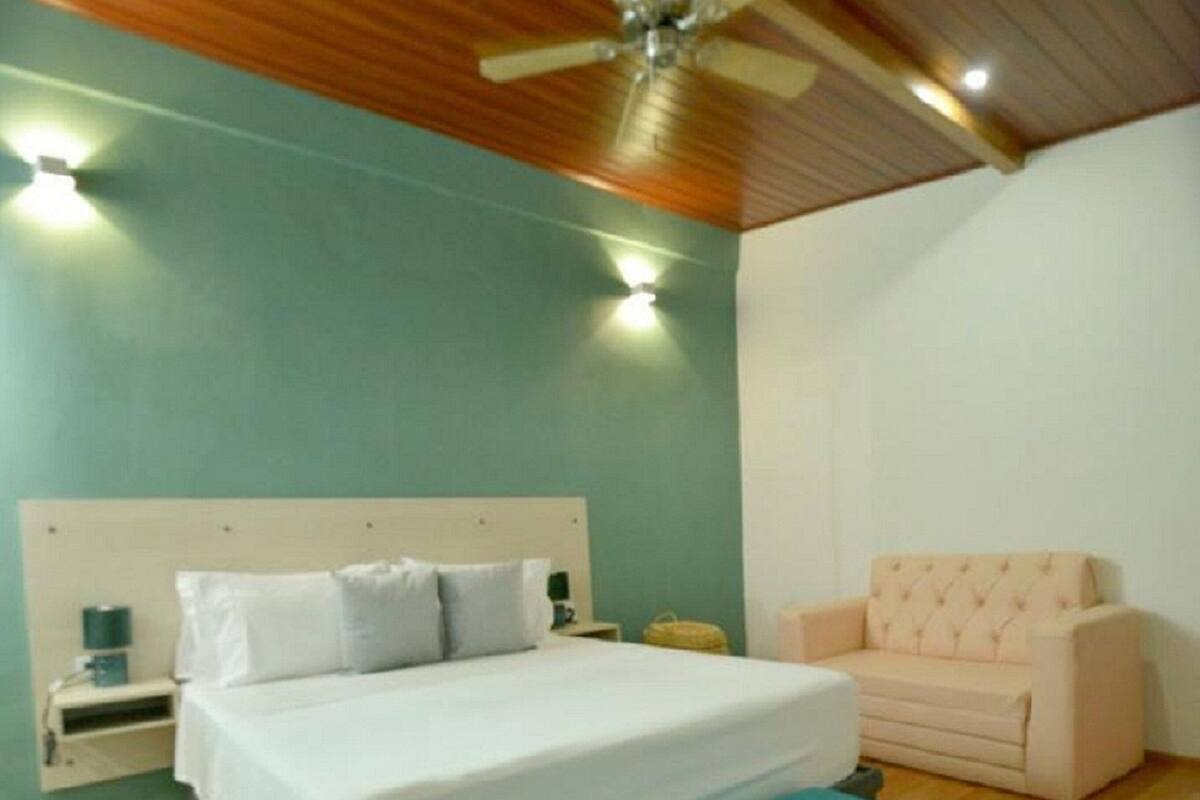 A bedroom with a bed, a bench, a nightstand, a lamp, and a ceiling fan.