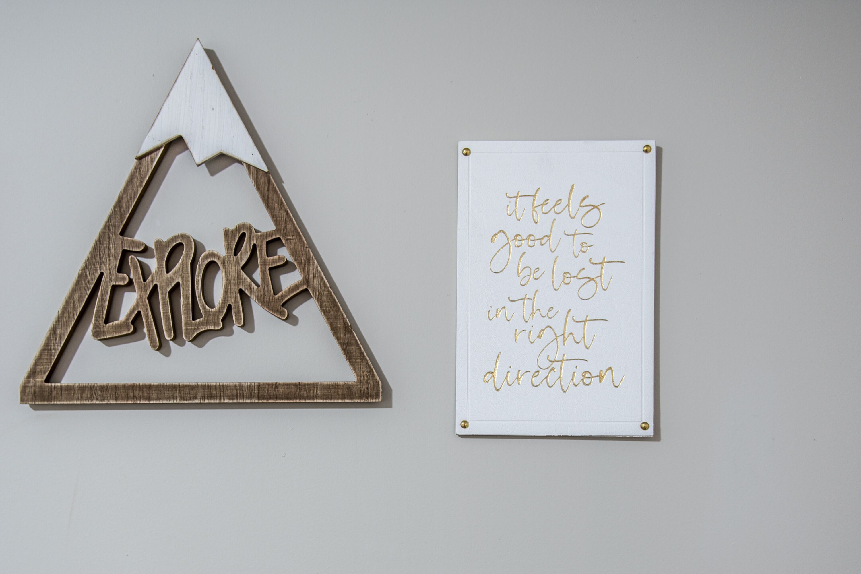 Un triangle en bois sur lequel est inscrit le mot « EXPLORE » et un tableau blanc sur lequel figure un message motivant.