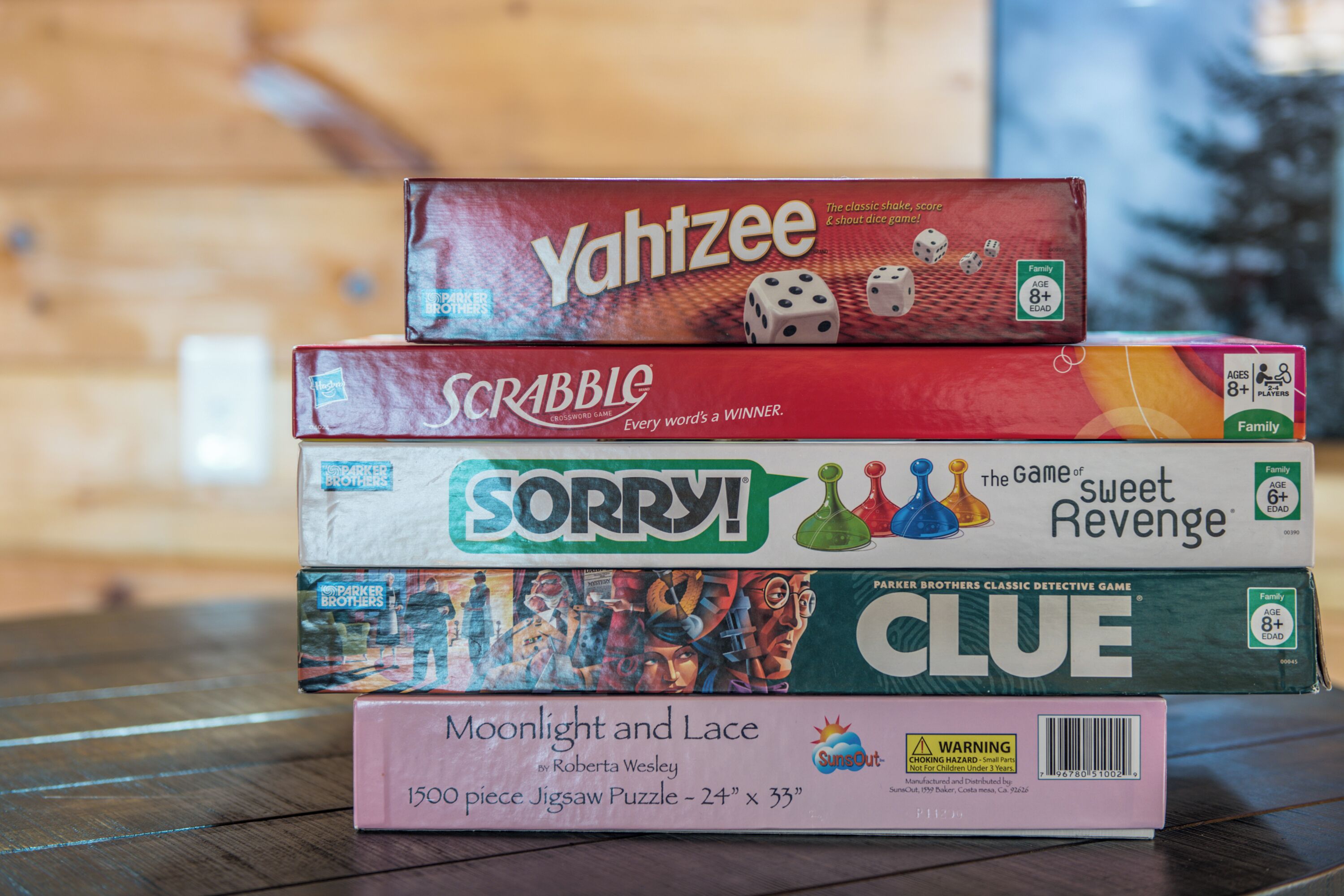 A stack of board games including Yahtzee, Scrabble, Sorry!, and others.
