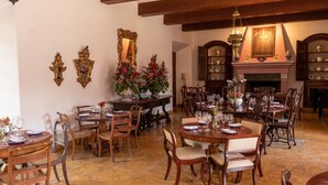 Un comedor con mesas y sillas de madera, una chimenea y espejos decorativos en las paredes.