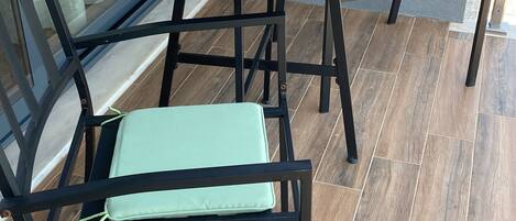 A patio area with a round table and two chairs, a small blue bowl, and a metal container on the table.