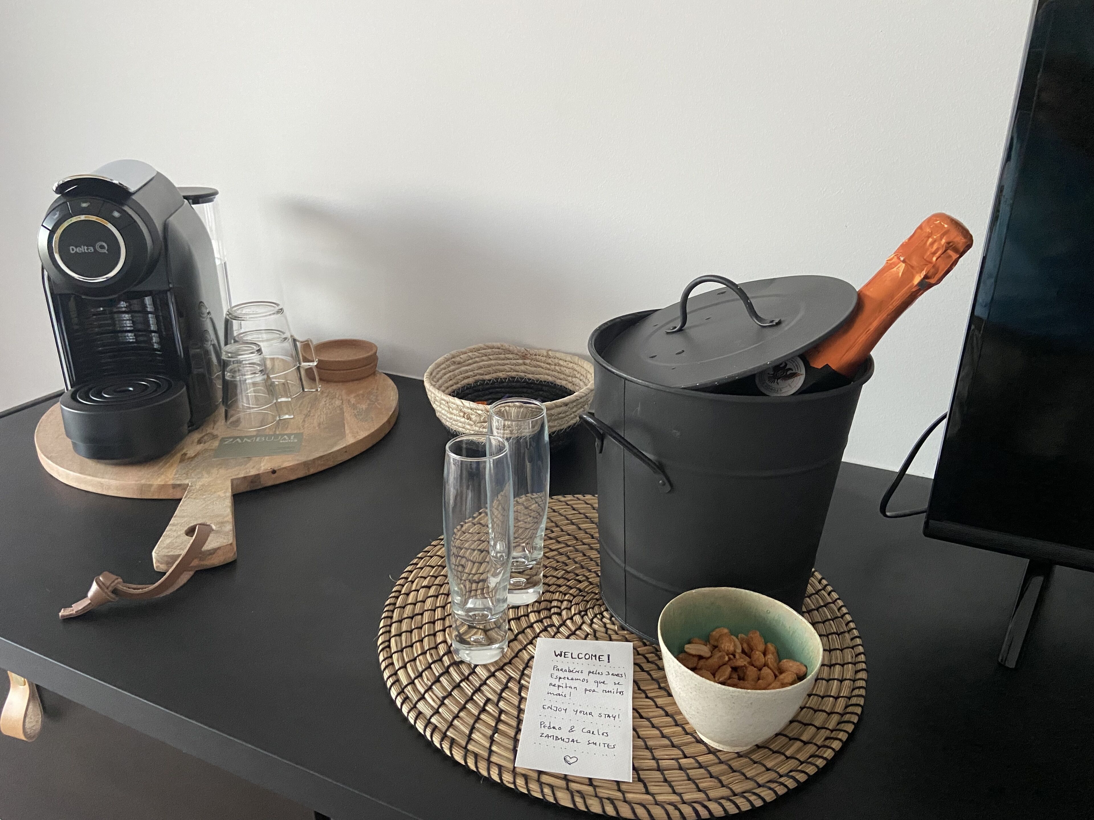 Un comptoir de cuisine avec une machine à café, des verres, une casserole et un bol de noix.