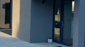 A modern building with a flat facade, large glass doors, and a small potted plant near the entrance. - Zambujal Suites (Sesimbra)
