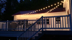 Une terrasse en bois, dotée d’une rambarde, mène à un bâtiment dont le toit est rouge.