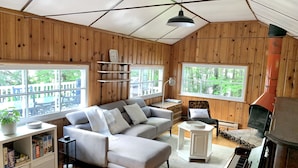 L’intérieur d’un chalet chaleureux, avec un canapé, un piano, une bibliothèque et une cheminée.