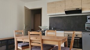 Eine kleine Küche mit Holzausstattung, einem eingebauten Ofen und einem Essbereich mit Tisch und Stühlen.